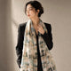 Muted green and beige landscape silk wrap worn long over a black blazer.