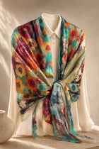 Teal, orange and plum floral silk wrap tied across a mannequin’s shoulders over a white blouse.