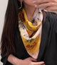 Yellow floral silk neckerchief with pale lace trim worn at the neck over black clothing.