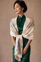 Champagne-blush botanical silk wrap tied across the shoulders over a green dress.