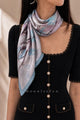 Blue and lilac landscape silk neckerchief with blue lace trim worn over a black dress.