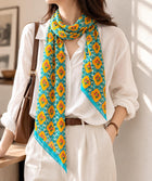 Teal and mustard floral long silk scarf worn loosely over a white shirt.