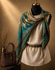 Teal and amber ornamental silk square draped diagonally over a mannequin’s shoulders.