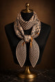 Paisley and black-and-tan houndstooth silk scarf knotted around a black mannequin's neck.