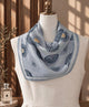 Blue-gray circular-print silk scarf draped around a mannequin’s neck.
